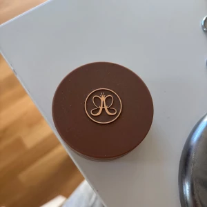 Anastasia Beverly Hills Cream Bronzer Golden Tan - Cream Bronzer i färgen Golden Tan från Anastasia Beverly Hills. Kommer i en rund plastburk med brunt lock och guldigt logotryck. Konsistensen är krämig och färgen är varm, medium-brun med solkysst ton. Perfekt för contouring och bronzing.