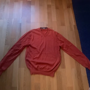 Orange v-ringad tröja från Ströms - Snygg orange v-ringad tröja från Ströms i storlek L. Tröjan är stickad och har långa ärmar med ribbade muddar vid ärmslut och nederkant. Perfekt för dig som gillar klassisk stil med en färgklick. Passar dig som vill ha en normal passform.