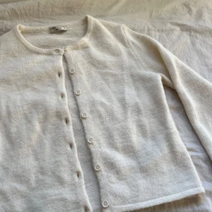 Vit kofta från Gina Tricot - Supermjuk vit/beige kofta från Gina Tricot i storlek s. Koftan är långärmad och har knäppning framtill med små vita knappar. Koftan har inga täcken på användning och är i bra skick