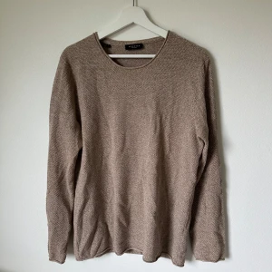 Beige stickad tröja från Selected Homme - Säljer en beige stickad tröja från Selected Homme i storlek L. Tröjan har rund halsringning och är långärmad, perfekt för lager-på-lager under kyligare dagar. Materialet är mjukt och ger en avslappnad men stilren look. 2N7