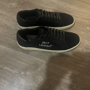 Saint Laurent skor - Svarta skor med vit text, svarta snören och vit sula. Passar både storlek 44 och 45, inte använda! Priset kan diskuteras!