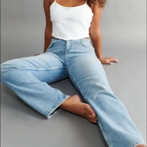 Ljusblåa wide jeans med hög midja - Säljer ett par ljusblåa jeans med hög midja och breda ben. Jeansen har klassisk femficksdesign, råa kanter vid benslut och är tillverkade i mjukt denimtyg. Perfekta för en avslappnad och trendig look.