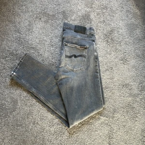 Nudie jeans grim Tim med slitningar - Märke: nudie jeans grim Tim.                            Storlek: w32 L32.                                                         Färg: grå 