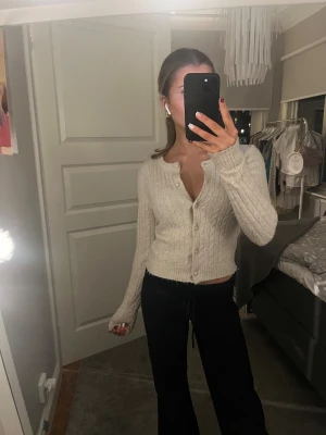 Ljusbeige stickad kofta med knappar - Superfin ljusbeige kofta med kabelstickat mönster och pärlknappar. Perfekt att slänga över en topp för en chill look. Mjuk och skön, passar till allt.