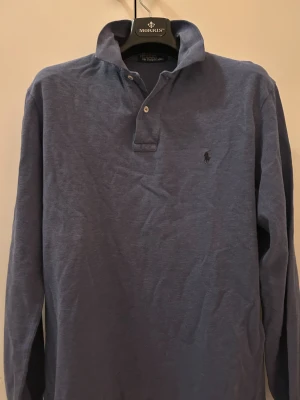 Långärmad piké Ralph Lauren - Fräsch långärmad piké från Ralph lauren, med knapp användning. Bra skick snygg tröja och passar till allt. Efterfrågad och snygg för priset. Skulle säga passar runt 175-185 cm. Kan ha kragen uppe eller nere! Skriv om funderingar osv!