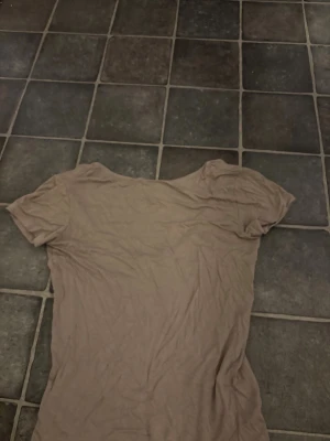 Beige t-shirt med v-ringning 157 - En enkel och mjuk beige t-shirt från 157 i storlek M. T-shirten har korta ärmar och öppen rygg ,Materialet känns som bomull och passformen är normal. Perfekt för en chill och avslappnad stil.
