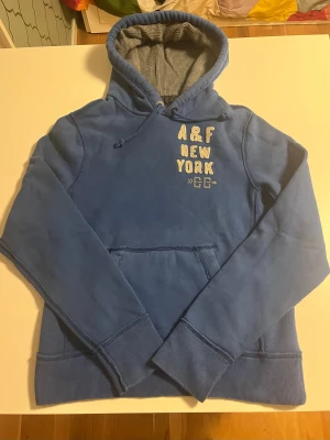 Abercrombie & fitch hoodie ny sällsynt - Abercrombie & fitch hoodie i blå färg. Otroligt fet och sällsynt. I helt perfekt skick inga defekter alls. Storlek L och passar 182-192 cm lång perfekt nu till vintern kolla gärna in mina andra annonser för mer snygga kläder och rabatt 😃