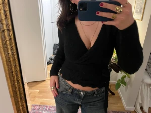 Svart omlottopp från & Other Stories - Svart omlottopp från & Other Stories med croppad passform och långa ärmar. Toppen har v-ringning och knyt i midjan.