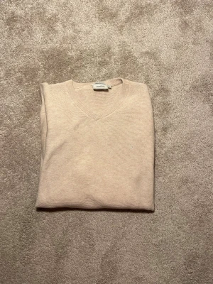 Beige v-ringad tröja från Boomerang - Stilren v-ringad tröja från Boomerang. 100% Organic cotton. Storlek L. Mycket fint skick. Priset ej hugget i sten. Hör av er vid frågor eller funderingar! 🍾