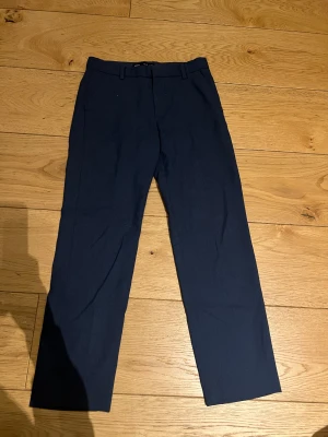 Blå Kostymbyxor - Blå kostymbyxor i storlek 140. Sitter bra och är i mycket fint skick utan fläckar eller hål. Bekväma och välgjorda.