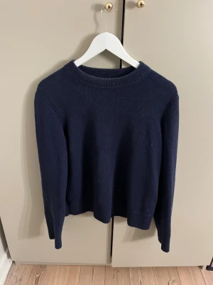 Mörkblå kashmirtröja från COS - Säljer min fina mörkblåa stickad tröja från COS i 100% kashmir. Tröjan har rund hals, ribbade muddar och lång ärm. 