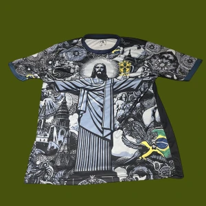 Ronaldinho Brasil kortärmad fotbollströja - Unik Brasilien fotbollströja med Ronaldinho och nummer 10 på ryggen. Framsidan har ett detaljerat konstnärligt tryck med Kristusstatyn, brasilianska motiv och flagga. Svart bas med inslag av grått, blått och gult. Kortärmad, rund hals och tillverkad i lätt polyester.