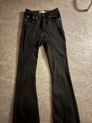 Svarta Lager 157 bootcut jeans - Svarta Lager 157  jeans med klassisk bootcut passform. Snygga femficksjeans med silverfärgade nitar och knapp, tillverkade i slitstarkt jeanstyg. Perfekta för dig som gillar retrovibbar och vill ha en cool siluett.