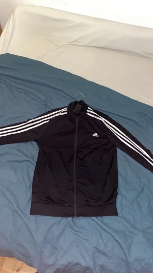 Adidas kofta - Säljer en Adidas kofta, unisex, stl 13-14y, okej skick, den har ett litet hål på bröstet men man lägger inte märke till det.