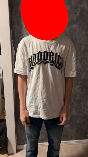 Hoodrich tshirt - Vit t-shirt från Hoodrich i storlek S med stort svart tryck på bröstet. Klassisk rund hals och korta ärmar. Tillverkad i mjuk bomull för skön känsla. Perfekt för dig som gillar streetwear och vill sticka ut med en fet logga.
