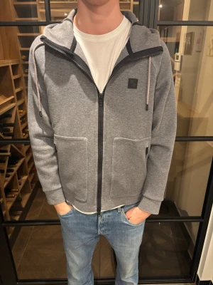 Woolwich zip-up hoodie  - Snygg grå hoodie från Woolrich i storlek S. Hoodien har hel dragkedja, två stora fickor fram och justerbar huva med snören. Tillverkad i mjukt sweatshirtmaterial och har en diskret logga på bröstet. Riktigt bra skick, inga defekter hittade och riktigt snygg passform. Storleken är S men skulle säga mer åt M hållet i verkligheten! Pris: 1399kr