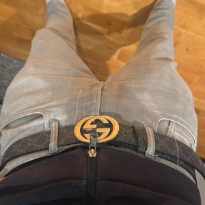 Gucci GG Supreme bälte svart/guld - Snyggt svart bälte från Gucci med GG Supreme-mönster och en stor, rund guldfärgad GG-logga som spänne. Bältet är gjort i canvas med läderdetaljer och har en lyxig vibe som lyfter vilken outfit som helst.