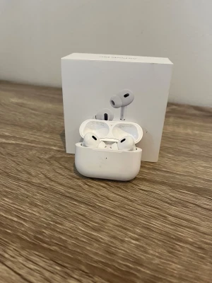 AirPods Pro - Apple AirPods Pro med originalförpackning. Trådlösa hörlurar med aktiv brusreducering och laddningsetui. Viss smuts och slitage syns på etuiet, men hörlurarna är i gott skick och fungerar utmärkt. Perfekt för musik, samtal och träning. Orginal etui med hörlurarna i sig utbyta till nya! AirPods Pro 2 (2023)