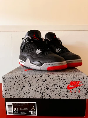 Nike Air Jordan 4 Retro Black/Red - Säljer ett par Nike Air Jordan 4 Retro i svart, rött och grått. Skorna har klassisk mesh och skinn på ovandelen. Skorna köptes i London i en affär som heter OGkicks, har digitalt kvitto och allt det originella som man får med i. Skorna är så gott som nya då jag bara använt dem ungefär 15gånger. Har du några frågor så är det bara att skriva till mig🙃