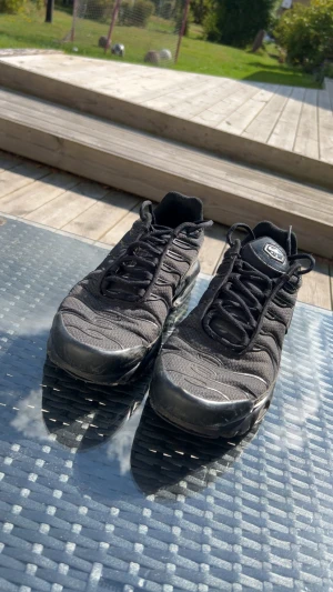 Nike tns - Säljer ett par helsvarta Nike Air Max Plus TN med klassisk Tn-detalj på hälen. Skorna har mesh- och syntetöverdel, vågiga linjer och synlig Air Max-dämpning i sulan. Snygg streetstil med snörning och diskret Swoosh på sidan.