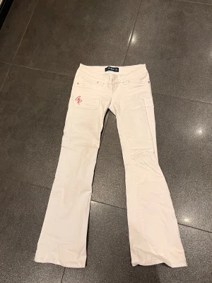 Vita bootcut jeans från G rise  - Snygga vita jeans från g rise med bootcut passform och låg midja. Byxorna har guldiga nitar och knappar, samt rosa broderad GR-logga på fickan. Storlek S/regular, passar perfekt på mig som är 168cm. Nypris är 1329