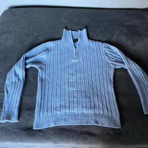 Ljusblå halv zip stickad tröja Steel - Säljer en ljusblå stickad tröja från Steel i storlek L men den sitter bättre som en M. Tröjan har ribbad struktur, lång ärm och en hög krage med half zip-dragkedja. Tröjan är i fint skick.