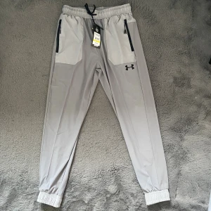 Under Armour byxor grå  - Under armour byxor i grå färg med svart logo. Byxorn är nya aldrig använda och kommer med tags. Storlek L men passar M. PRISET KAN DISKUTERAS 