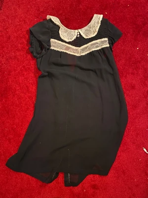 svart och vit kort klänning med spetskrage - jättesöt svart kort klänning i chiffong med vit spetskrage och spetsdetaljer över bröstet. puffiga korta ärmar och knappar längs ryggen. genomskinlig