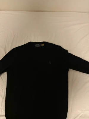 Merinoull polo Ralph lauren  - Svart långärmad tröja från Polo Ralph Lauren i tvättbar merinoull. Slim fit och passar perfekt för dig med storlek S/M stilren design som funkar till många olika looks. Hör av dig vid minsta funderingar!!!