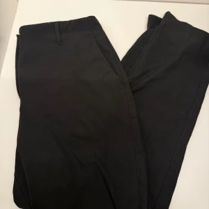 Svarta kostymbyxor  - Stilrena svarta kostymbyxor i mjukt bomullstyg. Klassisk passform med hällor för bälte och raka ben. Perfekta för en clean och snygg look.