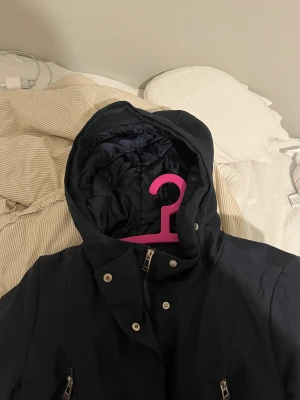  parkajacka Vero Moda - Mörkblå Vinterjacka från Vero Moda för damer i nyskick. Värmer otroligt bra och är bekväm. Borttagbar päls från huvan & fyra fickor på utsidan barav två har dragkejdor (se bild). Har både knappar och dragkedja. Storlek 38/M