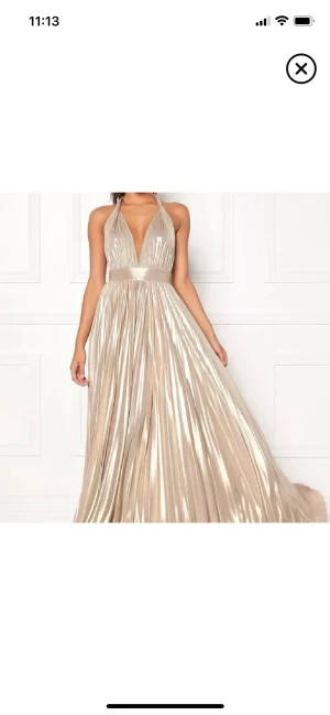 Champagnefärgad långklänning Goddiva - Champagnefärgad långklänning från Goddiva med plisserad kjol, djup v-ringning och öppen rygg. Klänningen har bred midja och knyt i nacken. Perfekt för bal, student eller nyår, jättefin färg!💗Säljer för att den inte kommit till användning, pris går att diskutera