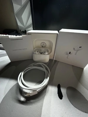 AirPods Pro 2 - Säljer ett par AirPods Pro 2 i mycket fint skick, komplett med originalkartong och USB-C laddningskabel. Hörlurarna och laddningsfodralet är rena och utan synligt slitage. Perfekt för dig som vill ha aktiv brusreducering och hög ljudkvalitet.