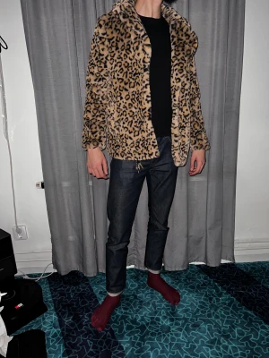 Leopardmönstrad pälsjacka - Säljer en snygg pälsjacka med leopardmönster i beige och bruna toner. Jackan har en loose passform, krage och är långärmad. Materialet är mjuk syntetpäls som ger en cool och trendig vibe. Perfekt för dig som vill sticka ut och addera lite edge till din outfit.