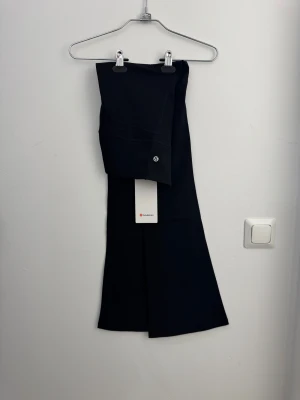 Svarta bootcut/flared leggings/tights från Lululemon i storlek 4 - Svarta leggings från Lululemon Groove-serien med hög midja och diskret logga på benet. Tillverkade i supermjukt Nulu-material med fyrvägsstretch och dold ficka i linningen. Perfekta för träning eller chill, sitter skönt och följer kroppen.