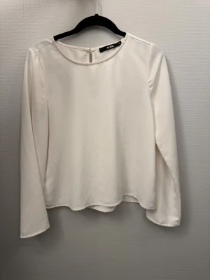 Vit långärmad blus från Bik Bok - Säljer en stilren vit blus från Bik Bok i storlek xs. Blusen har rund halsringning, långa ärmar och knäppning bak i nacken. Materialet är mjukt och har en lätt glansig finish som ger en elegant känsla. Perfekt att matcha med jeans eller kjol.