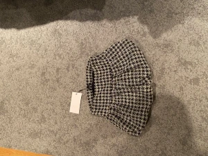 Svartvit rutig kortkjol från Zara - Supersnygg svartvit kortkjol från Zara i storlek S med klassiskt rutigt mönster. Kjolen har en lätt utställd form och är tillverkad i ett grovt, strukturerat tyg som ger en cool och trendig vibe. Perfekt att matcha med boots och en stickad tröja och går att både klä upp och ner❤️