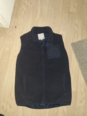 Mörkblå Fleece väst - Jag säljer denna tvärfeta mörkblåa fleece västen från lager 157, storlek 160 men passar mig som är 175 skulle även säga att den passar strl 182, den går längre inte att köpa och flera personer har frågat mig om den vid användning!! Den sitter tajt och hänger inte ut vid sidorna🫱🏼‍🫲🏽 Hör gärna av er vid funderingar eller prisförslag🙌🏼 