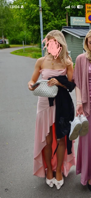 Balklänning  - Säljer en ljusrosa långklänning med asymmetrisk volangkant och smala axelband. Klänningen har öppen rygg med snygg snörning och är gjord i ett glansigt satinliknande material som faller fint. Perfekt för bal eller student! 💗Använt 1 gång! 10/10 skick. Köpte för 1400kr