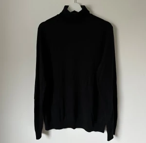 Svart polotröja från Selected Homme - Svart polotröja från Selected Homme i storlek M. Tröjan har klassisk hög krage och långa ärmar, perfekt för lager-på-lager. Materialet är mjukt och skönt, tillverkat i bomull. Enkel och stilren design som funkar till många olika looks. 5H13