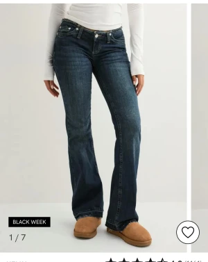 Blå bootcut jeans med låg midja - nypris 700kr Snygga mörkblå jeans med bootcut passform och låg midja. Jeansen har klassisk femficksdesign, knapp och dragkedja framtill samt slitningar för en cool look. Perfekta för dig som gillar retrovibbar och vill ha ett avslappnat men trendigt plagg. 