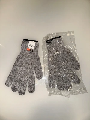 Grå stickade skyddshandskar Level 5 - Skärskyddshandskar – Klass 5 Erbjuder En Hög Nivå Av Säkerhet För Dina Händer Vid Köksaktiviteter Och Trädgårdsarbete. Tillverkade Med HPPE-Material (Högpresterande Polyeten) Ger Dessa Handskar Ett Effektivt Skydd Mot Skärskador Och Repor. Den Avancerade Teknologin Gör Handskarna Både Lätta Och Bekväma Att Bära, Samtidigt Som De Bibehåller En Hög Grad Av Skärsäkerhet.Dessa Handskar Är Särskilt Utformade För Att Möta Kraven För Glas- Och Köksskärning, Vilket Ger Pålitligt Skydd Utan Att Kompromis
