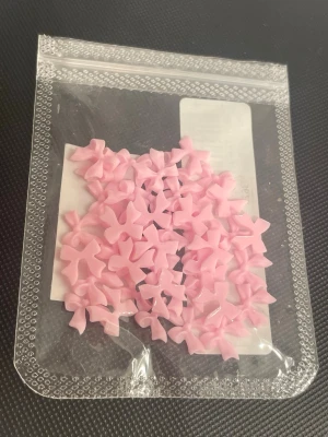Rosa rosetter för nageldekoration - Säljer ett paket med små ljusrosa rosetter i plast, perfekta som dekoration till naglar. Rosetterna är tredimensionella och har en söt, feminin look som ger dina naglar en extra touch. Kommer i en återförslutningsbar plastpåse och passar till nail art.