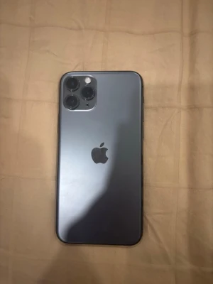 iPhone 11 Pro - Snygg iPhone 11 Pro i grått med trippelkamera och elegant design. Telefonen ser ut att vara i gott skick utan synliga sprickor eller större repor. Perfekt för dig som vill ha en kraftfull och stilren smartphone med utmärkt kamera och prestanda.