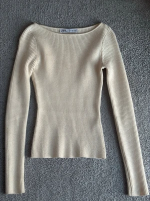 Ribbad beige långärmad tröja Zara - Säljer en ribbad, beige långärmad tröja från Zara. Tröjan har en kroppsnära passform och rundad halsringning. Perfekt basplagg till garderoben och enkel att styla med olika outfits.