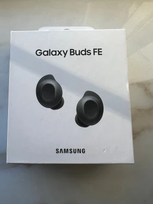 Galaxy Buds FE - Samsung Galaxy Buds FE trådlösa hörlurar i mycket fint skick. Komplett med laddningsetui och originalförpackning. Perfekt för musik, samtal och träning. Inga synliga defekter eller slitage, ser ut att vara sparsamt använda.
