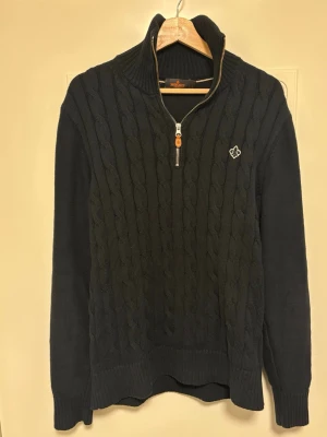 Svart kabelstickad half zip från morris - Svart kabelstickad half zip från morris. Mycket bra skick inga fläckar eller skador. Storlek: Large Säljs då jag rensar garderoben.