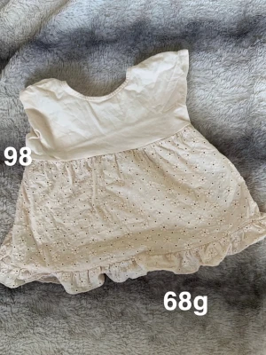  blus med broderade blommor - Söt blus med broderade blommor och volangkant nedtill. Blusen har korta ärmar och rund halsringning. Perfekt för varma dagar och ger en romantisk touch till outfiten.🌸 Fint använt skick. Storlek 98