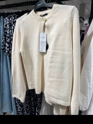 Beige kofta från Gina Tricot - Säljer en stilren beige kofta från Gina Tricot. Koftan har rund halsringning, ribbade muddar och en knapp framtill. Perfekt att slänga över en topp för en enkel men snygg look. Materialet känns mjukt och skönt mot huden. Bra skick men finns tecken på användning därav priset 
