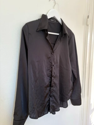 Elegant svart silkes skjorta  - Svart skjorta i silkesliknande material från SHEIN 🖤 Mjuk, lätt och elegant – passar perfekt till vardag, jobb eller fest. Stilren och tidlös modell som enkelt matchas med byxor, kjol eller jeans.  ▫️ Märke: SHEIN ▫️ Storlek: S ▫️ Skick: Bra / knappt använd  Hör av dig vid frågor eller intresse ✨